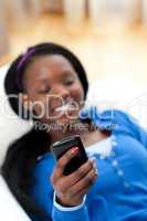 Charming woman sending a text lying on a sofa