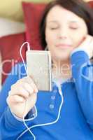 Caucasian young woman listening music lying on a sofa
