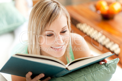 Bright woman reading a book lying on a sofa