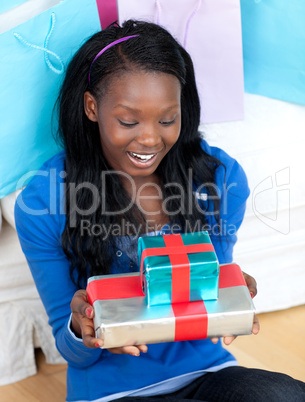 Smiling woman holding a present sitting on the floor