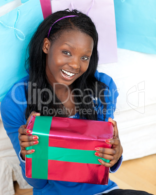 Jolly woman holding a present sitting on the floor