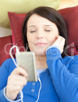 Brunette young woman listening music lying on a sofa