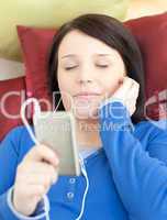 Brunette young woman listening music lying on a sofa