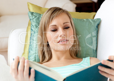 Beautiful woman reading a book lying on a sofa