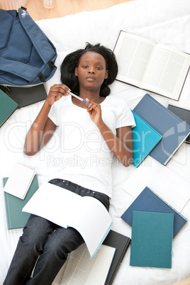Serious teen girl studying lying on her bed