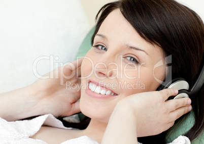 Positive teen girl listening music lying on a sofa