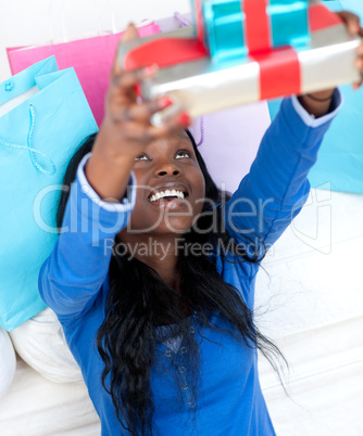Happy woman holding a present sitting on the floor