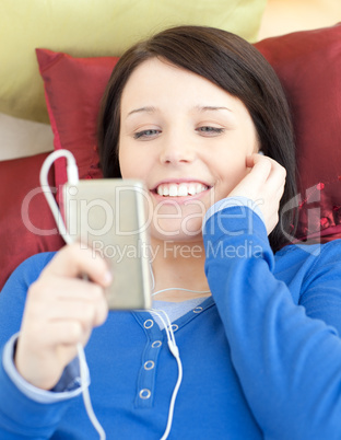 Pretty young woman listening music lying on a sofa