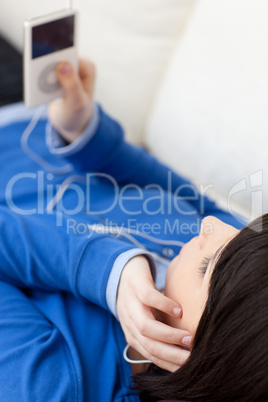 Close-up of a brunette young woman listening music lying on a so