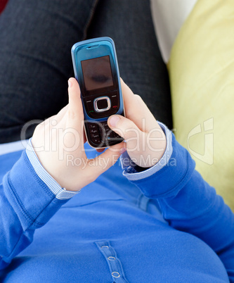 Close-up of a woman sending a text lying on a sofa