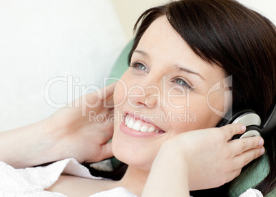 Happy teen girl listening music lying on a sofa