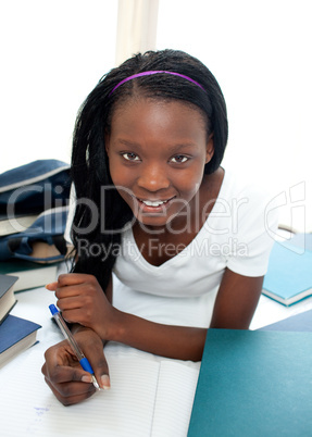 Smiling teen girl studying lying on her bed