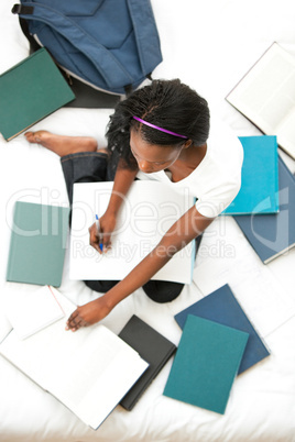 Concentrated teen girl studying sitting on her bed