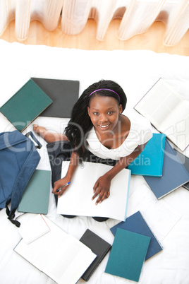 Cheerful teen girl studying sitting on her bed