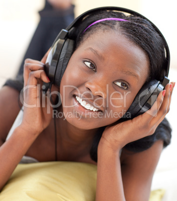 Smiling woman listening music lying on a sofa