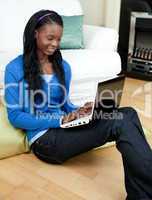 Afro-american woman using a laptop sitting on the floor