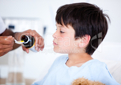 Cute sick little boy taking medicine