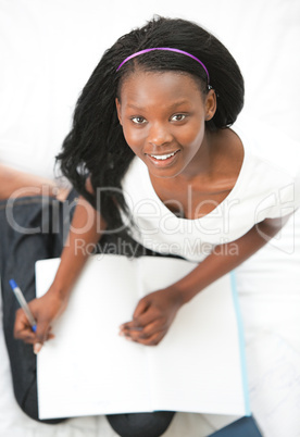 Happy teen girl studying sitting on her bed