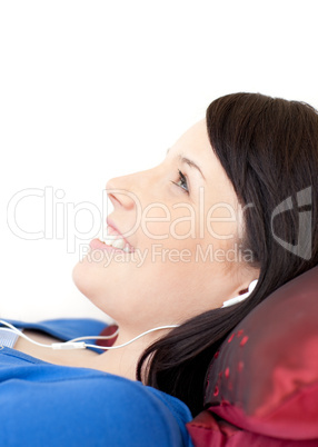 Cheerful teen girl listening music lying on a sofa