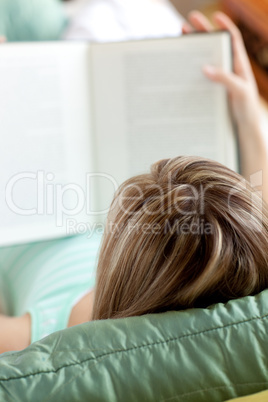 Woman reading a book lying on a sofa