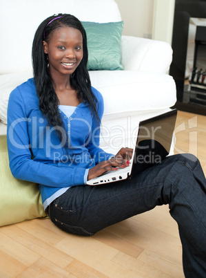Charming woman using a laptop sitting on the floor