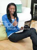 Happy woman using a laptop sitting on the floor