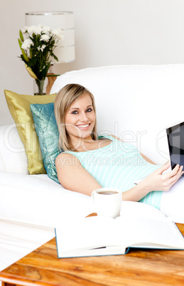 Cheerful woman surfing the internet lying on a sofa
