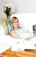 Cheerful woman surfing the internet lying on a sofa