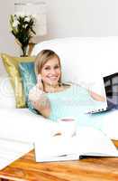 Jolly woman surfing the internet lying on a sofa