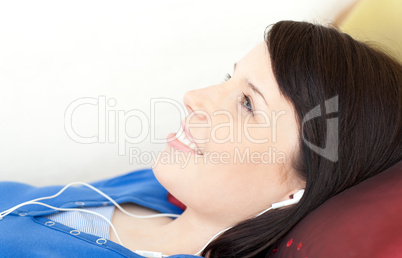 Smiling teen girl listening music lying on a sofa
