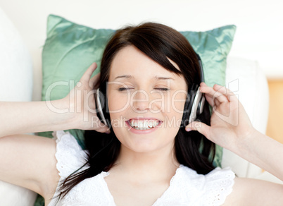 Jolly teen girl listening music lying on a sofa