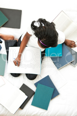 Serious teen girl studying sitting on her bed