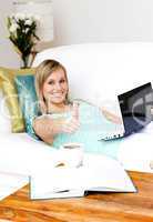 Charming woman surfing the internet lying on a sofa