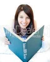 Portrait of a charming teen girl studying lying on a bed