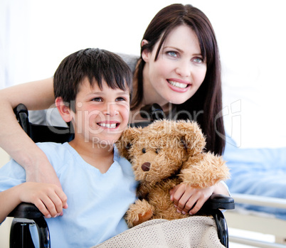 Smiling little boy in a wheelchair with his mother