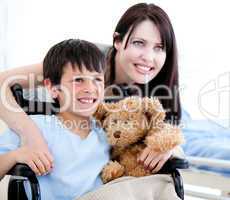 Smiling little boy in a wheelchair with his mother