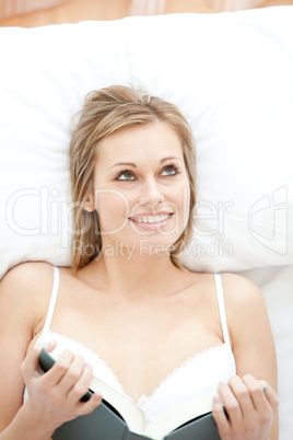 Smiling woman reading lying on her bed