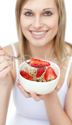 Jolly woman eating cereals with strawberries