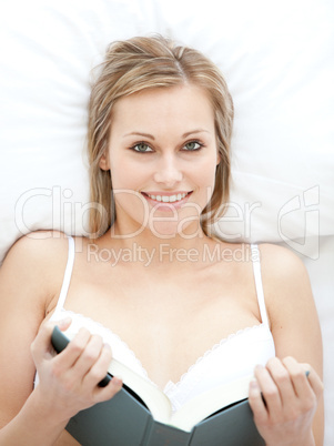 Blond woman reading lying on her bed