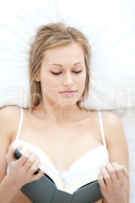 Attractive woman reading lying on her bed