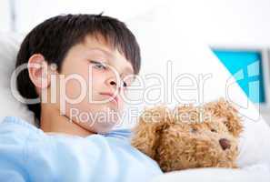 Portrait of a sick boy lying in a hospital bed