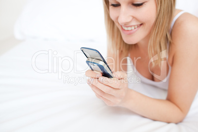 Close-up of a woman sending a text lying on her bed