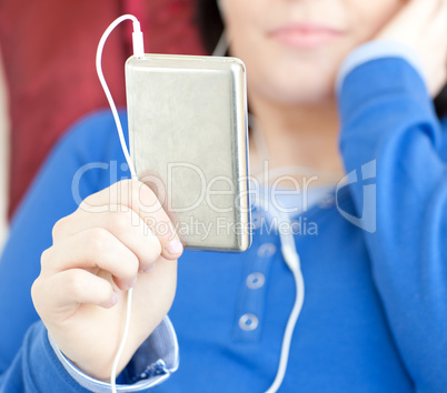 Close-up of a brunette teen girl listening music lying on a sofa