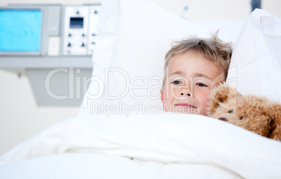 Sick cute little boy lying in a hospital bed