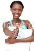 Cheerful fitness woman with thumb up holding a weight scale