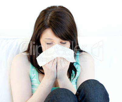 Sick teen girl blowing sitting on a sofa