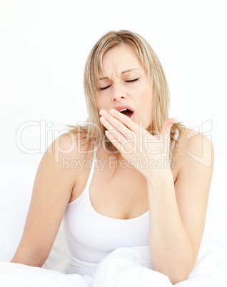 Exhausted woman yawning sitting on her bed