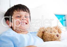 Smiling little boy lying in a hospital bed