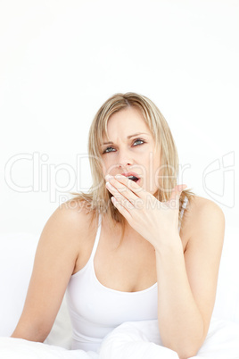 Tired woman yawning sitting on her bed