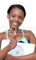 Charming fitness woman with thumb up holding a weight scale